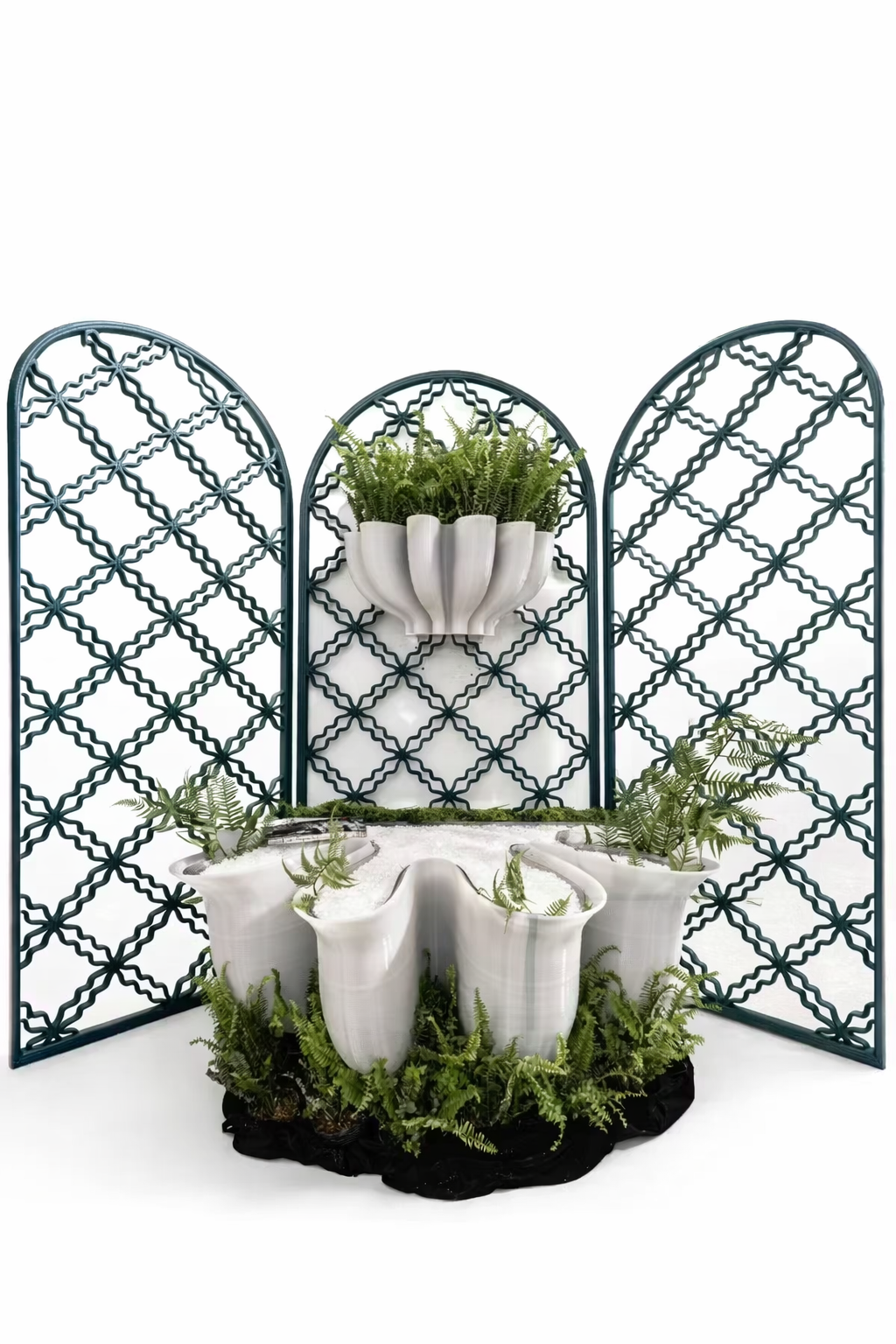 White sculptural planter with greenery displayed in front of patterned screens